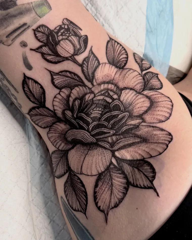 Black and grey peony tattoo on a hip and ribs